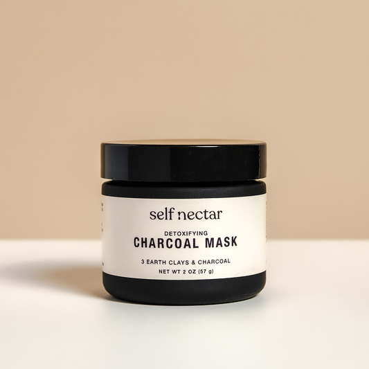 A purifying detoxifying charcoal mask in a sleek container on a neutral-colored surface. The product is labeled as a charcoal mask, showcasing a clean and minimalist design for an invigorating and clarifying skincare experience.