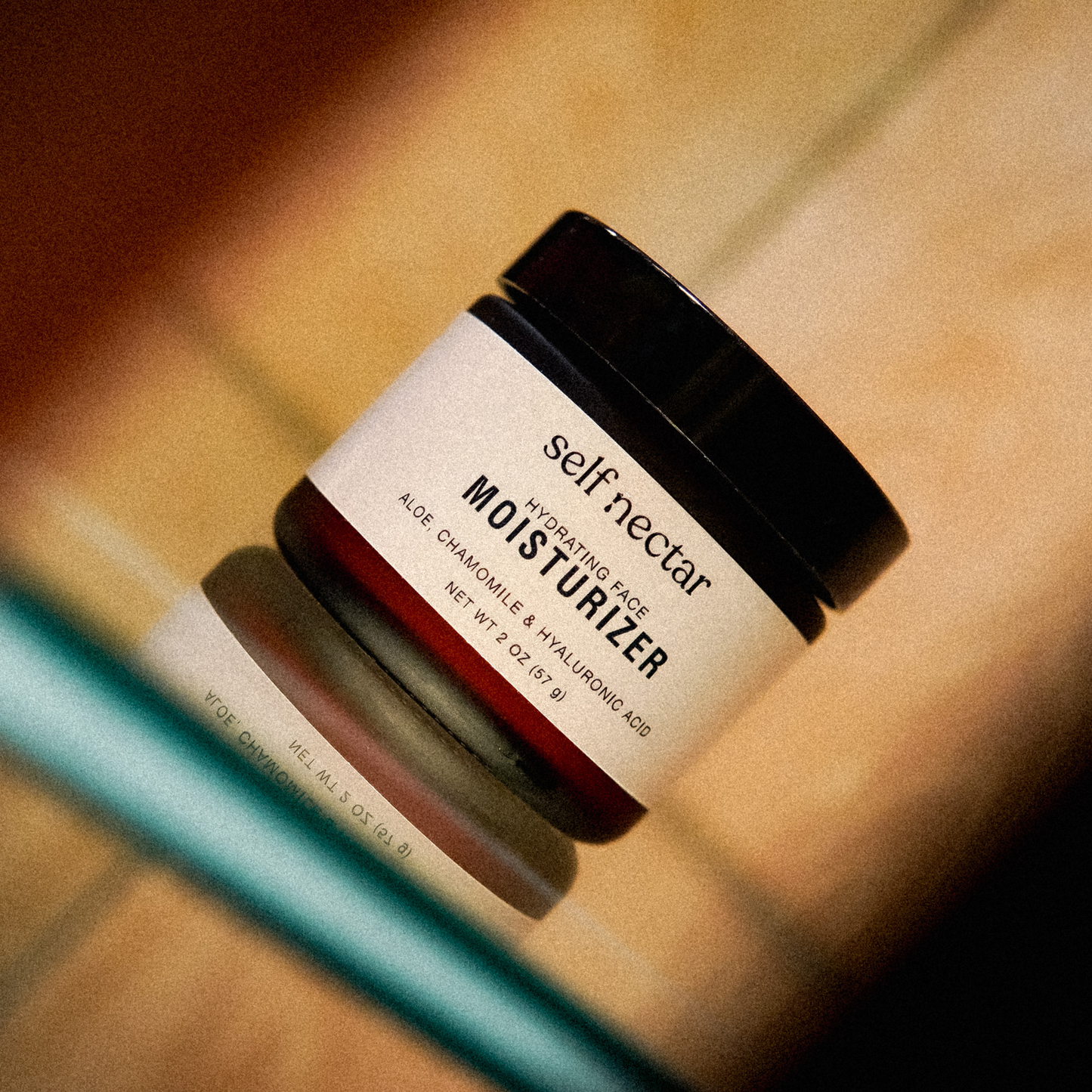 A captivating moody-toned photograph of the hydrating face moisturizer nestled among other products on a shelf. The amber container stands out in the atmospheric lighting, evoking a sense of sophistication and luxury within the skincare collection.