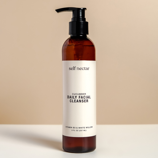 A refreshing cucumber daily facial cleanser in a sleek amber bottle with a pump dispenser on a neutral-colored surface. The product is labeled as a daily facial cleanser, featuring a clean and minimalist design for a revitalizing skincare routine.